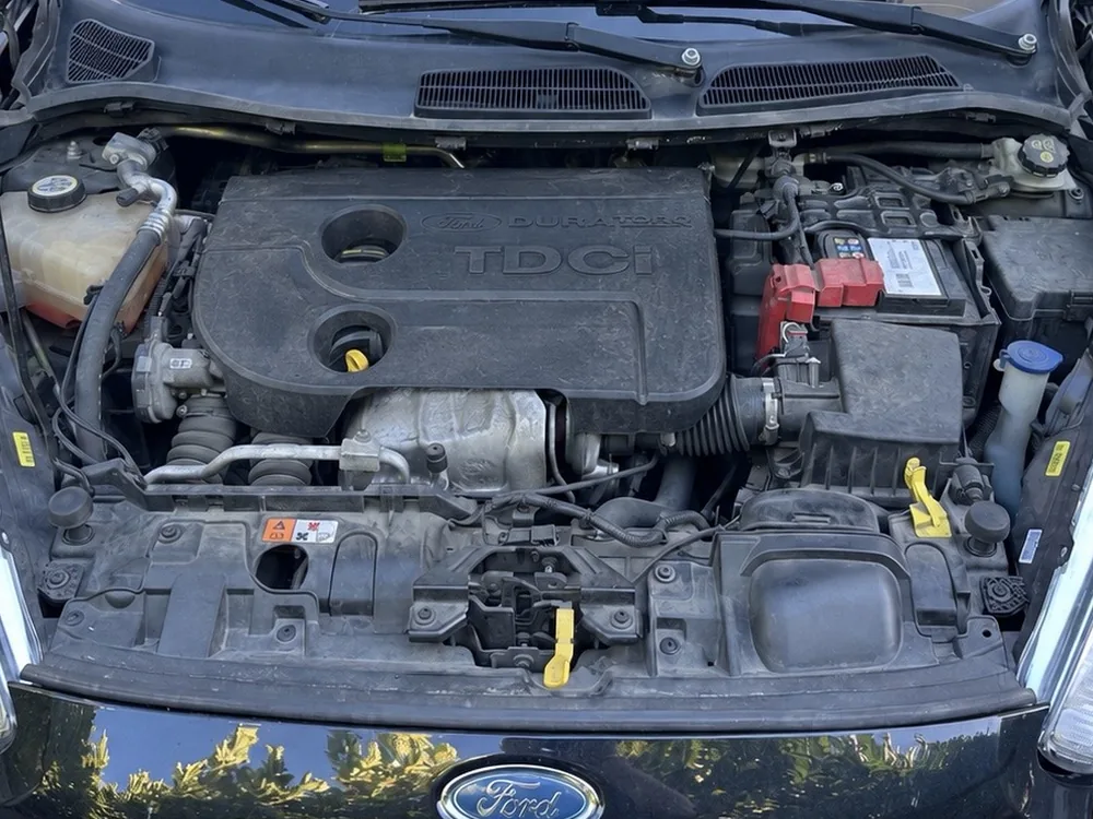 Compartiment moteur d’une Ford Fiesta TDCi avant nettoyage : plastiques gris et poussiéreux